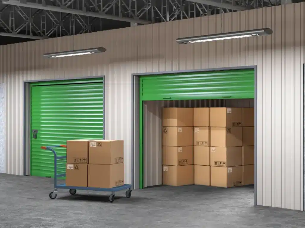 Cartons empilés dans un box de garde-meuble avec porte verte dans un entrepôt sécurisé